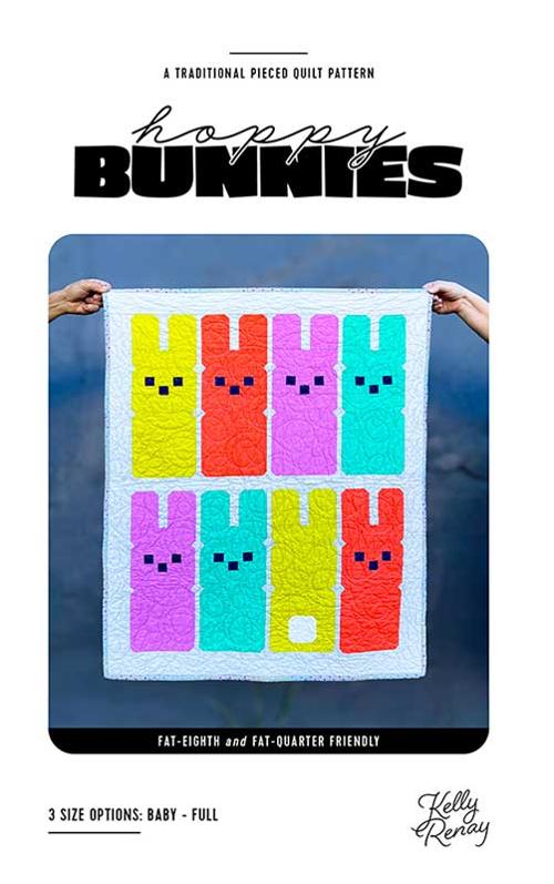 Colorful quilt pattern featuring bunnies held by hands against a blue background
