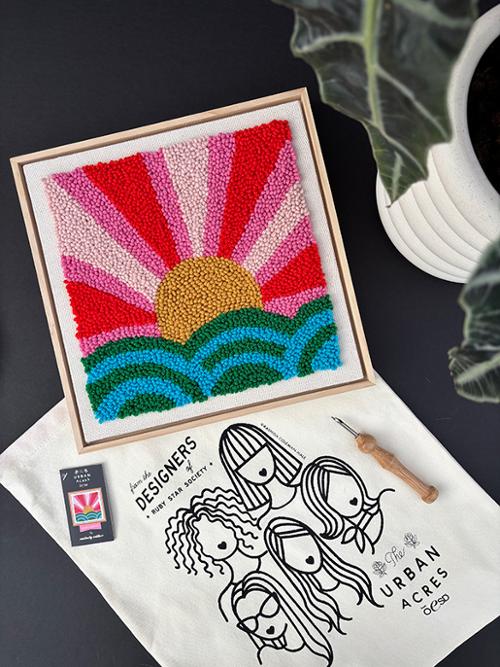 Colorful sun and wave design on a framed piece of art with a coffee cup and plant in the background.